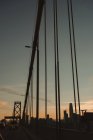 Famosa suspensão Bay Bridge em San Francisco com carros em movimento contra o céu nublado durante o nascer do sol — Fotografia de Stock