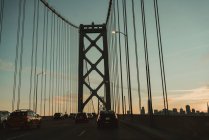 Célèbre pont suspendu Bay à San Francisco avec des voitures en mouvement contre le ciel nuageux pendant le lever du soleil — Photo de stock
