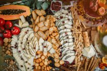 Верхний вид разнообразных сыров и крекеров, поставленных на стол с кондитерскими изделиями и свежими фруктами — стоковое фото