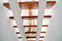 Низкий угол обзора невесты на высоких каблуках и элегантное свадебное платье, идущее по деревянной лестнице — стоковое фото