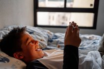 Ragazzo deliziato utilizzando tablet in camera da letto durante il fine settimana — Foto stock
