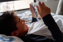 Чудовий хлопчик використовує планшет у спальні під час вихідних — стокове фото