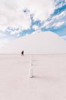 Неузнаваемый человек идет по пустой площади рядом с белым изогнутым зданием Международного культурного центра Оскара Нимейера, расположенного в Астурии в Испании в солнечные дни на фоне синего облачного неба — стоковое фото