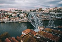 Drone view of amazing cityscape with bridge over calm river and residential houses under sunset cloudy sky — Stock Photo