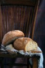 Loafs de pão saboroso e faca colocada em pedaço de pano na cadeira de madeira — Fotografia de Stock