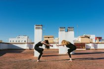 Women practicing yoga together on rooftop — Stock Photo