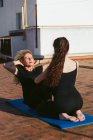 Women practicing partner yoga on rooftop — Stock Photo