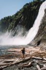 View of girl walking alone on wet sand beach close to waterfall on a sunny day — Stock Photo