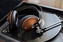 Vintage-Kopfhörer aus Holz befinden sich auf einer schwarzen Schallplatte im Plattenspieler — Stockfoto