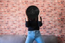 Jeune femme anonyme tenant un vinyle noir avec ses mains — Photo de stock