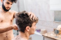 Чоловік з тримером для стрижки волосся хлопця у сучасній ванній вдома — стокове фото
