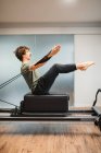 Seitenansicht des Sportlers in Aktivkleidung mit Pilates-Gerät und Stretcharmen mit Widerstandsbändern — Stockfoto