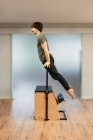 Vue latérale du sportif fort équilibrage sur les mains sur la chaise pilates pendant l'entraînement dans la salle de gym moderne — Photo de stock