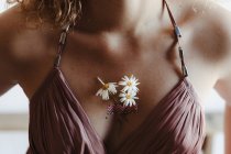 Cropped shot of female chest with silk dress details and sticky taped chamomile flowers — Stock Photo