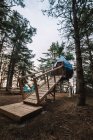 Низький кут розслабленого жіночого кемпера, що стоїть на дерев'яній платформі біля сучасного кемпінгу в лісі під час відпустки — стокове фото