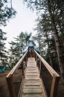 Низкий угол расслабленного женского кемпера, стоящего на деревянной платформе возле современного кемпинга в лесу во время отдыха — стоковое фото