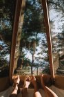 Pies de novio y novia acostados juntos en hamaca en casa de campo y admirando la vista de la madera a través de la ventana - foto de stock