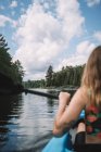 Vue de dos d'une voyageuse anonyme en gilet de sauvetage assise dans un bateau lors de l'exploration fluviale contre un ciel nuageux dans le parc national de la Mauricie au Québec, Canada — Photo de stock