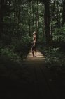 Жінка з рюкзаком стоїть на лісовій стежці і насолоджується погодою в зеленому лісі Національного парку Ла - Маурічі (Квебек, Канада). — стокове фото