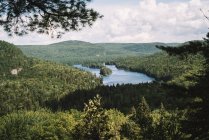Vue pittoresque d'un lac calme au milieu d'une forêt avec des arbres verts contre un ciel nuageux dans le parc national de la Mauricie au Québec, Canada — Photo de stock