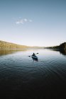 Silhueta de viajante anônima sentada no caiaque e remo durante a viagem no rio calmo no dia sem nuvens no Parque Nacional La Mauricie em Quebec, Canadá — Fotografia de Stock