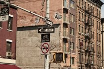 De baixo de um sentido sinais de trânsito na encruzilhada com edifícios altos modernos em segundo plano na cidade de Nova York — Fotografia de Stock