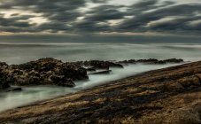 Paesaggio pittoresco di terreno roccioso, mentre le onde drammatiche schiantarsi rocce in Cantabria in grigio giorno coperto — Foto stock