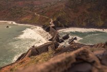 From above picturesque landscape of Gaztelugatxe island with long stone bridge passing through the seashore at windy day — Stock Photo