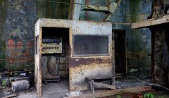 Cabine en métal rouillé avec équipement électrique à l'intérieur installé dans un ancien bâtiment industriel avec des murs grungy — Photo de stock