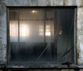 Fragment of weathered stone wall with small dirty window of derelict industrial building — Stock Photo
