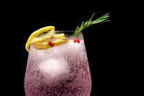 Джин тоник коктейль с розовой тонизирующей водой, розовый перец, розмарин, мята, корица, лимон и апельсин на темном фоне — стоковое фото