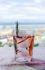 Джин тоник коктейль с розовой тонизирующей водой, розовый перец, розмарин, мята, корица, лимон и апельсин в солнечном свете на столе ресторана — стоковое фото