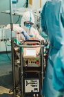 Médico profissional em uniforme de proteção e luvas de verificação de equipamentos antes de executar a operação na sala de cirurgia na clínica moderna — Fotografia de Stock