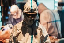 Cirujano cansado devastado en máscara protectora y uniforme saliendo del quirófano después de una operación dura en la clínica moderna - foto de stock