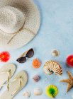 Top view of various seashells placed near colorful cocktail decorations and stylish summer accessories on blue plaster surface — Stock Photo
