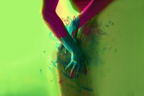 Cortar artista feminino irreconhecível coloração parede colorida com tinta em gradiente fundo colorido em estúdio — Fotografia de Stock