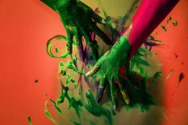 Crop unrecognizable female artist staining colorful wall with paint on gradient colorful background in studio — Stock Photo