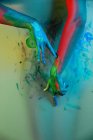 Неузнаваемая женщина-художник, окрашивающая красочную стену краской на градиентном красочном фоне в студии — стоковое фото