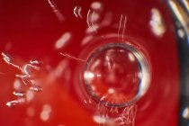 Крупним планом прозора бульбашка, що плаває на поверхні яскраво-червоного напою в скляній чашці — стокове фото