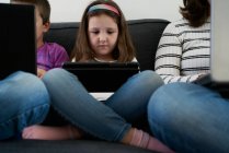 Sério mãe e crianças passar o tempo juntos usando gadgets no sofá em casa — Fotografia de Stock