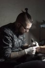 Татуїст використовує машину і робить татуювання з чорним чорнилом в салоні анонімного обрізаного клієнта — стокове фото