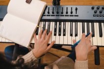 Зверху жінка-музикантка грає на електричному піаніно і створює музику в творчій домашній студії — стокове фото