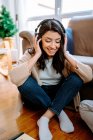 Fröhliche Musikerin hört Lied über Kopfhörer, während sie zu Hause Musik komponiert — Stockfoto
