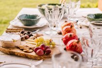 Mesa servida con vajilla y surtido de frutas maduras y deliciosos aperitivos en la terraza - foto de stock