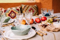 Table servie avec vaisselle et fruits mûrs assortis et délicieux apéritifs sur la terrasse — Photo de stock