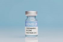 Glass vial with vaccine from COVID 19 placed on table on blue background — Stock Photo