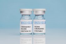 Frascos de vidro com vacina COVID 19 colocados sobre a mesa sobre fundo azul — Fotografia de Stock
