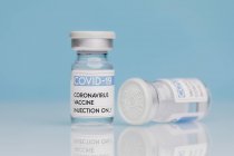 Glasflaschen mit Impfstoff von COVID 19 auf Tisch auf blauem Hintergrund — Stockfoto