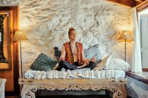 Hombre rubio practicando meditación con los ojos cerrados en casa - foto de stock