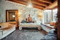 Hombre rubio practicando meditación con los ojos cerrados en casa - foto de stock